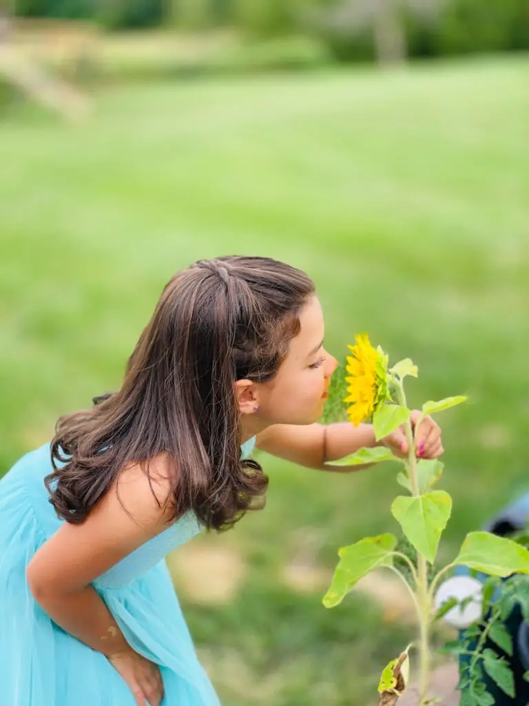 girl in blue tank top holding yellow flower during daytime