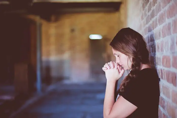 Woman praying at a wall