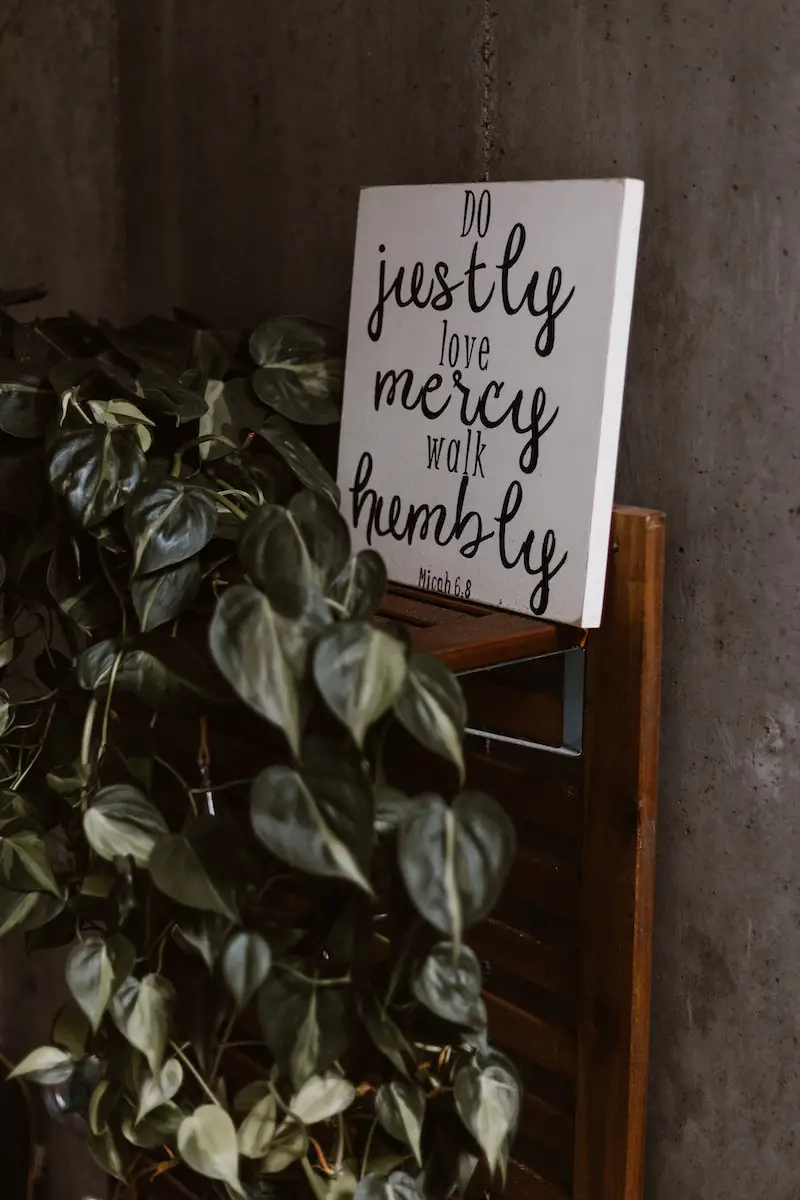 do justly love mercy walk humbly signage leaning on wall beside plants
